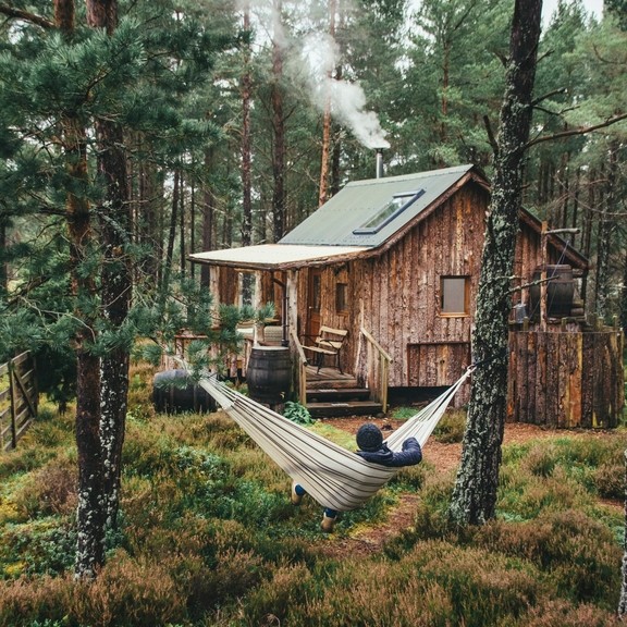 Person relaxing in hammock outside wood cabin