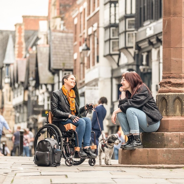 Two women sit talking together in a town centre