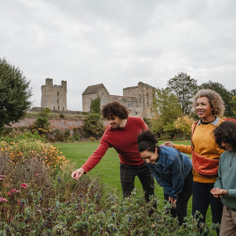 Family looking at flowers in a garden with ruins of a castle in the background