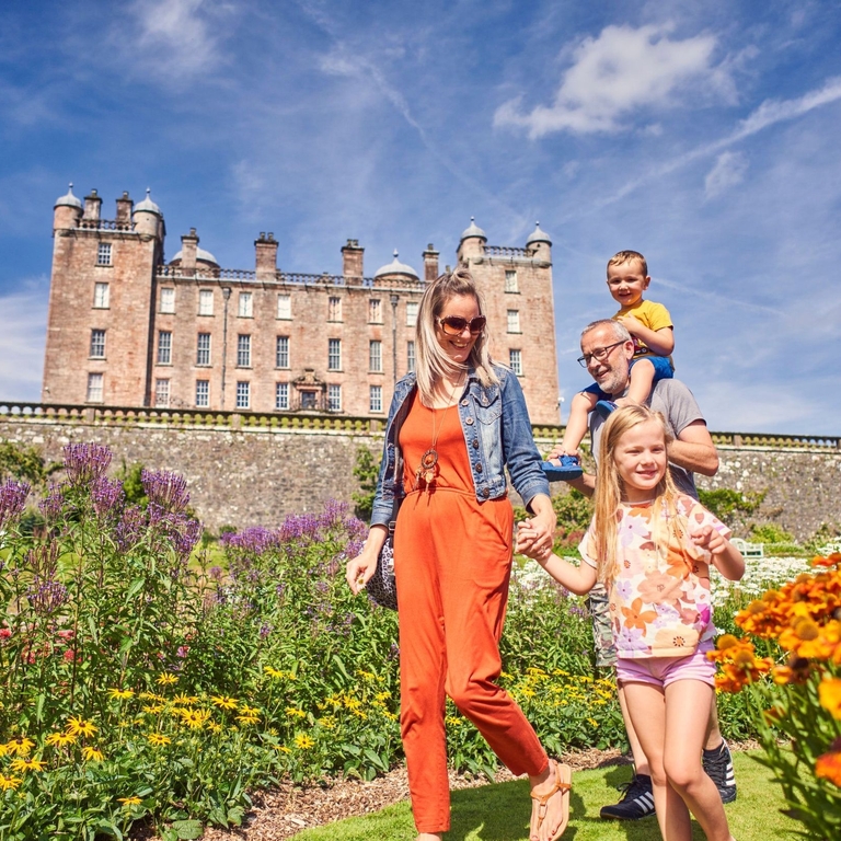 A young family walking through castle gardens.
