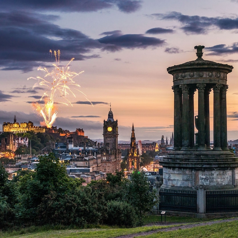 Fireworks at dusk in the sky over historic monument.