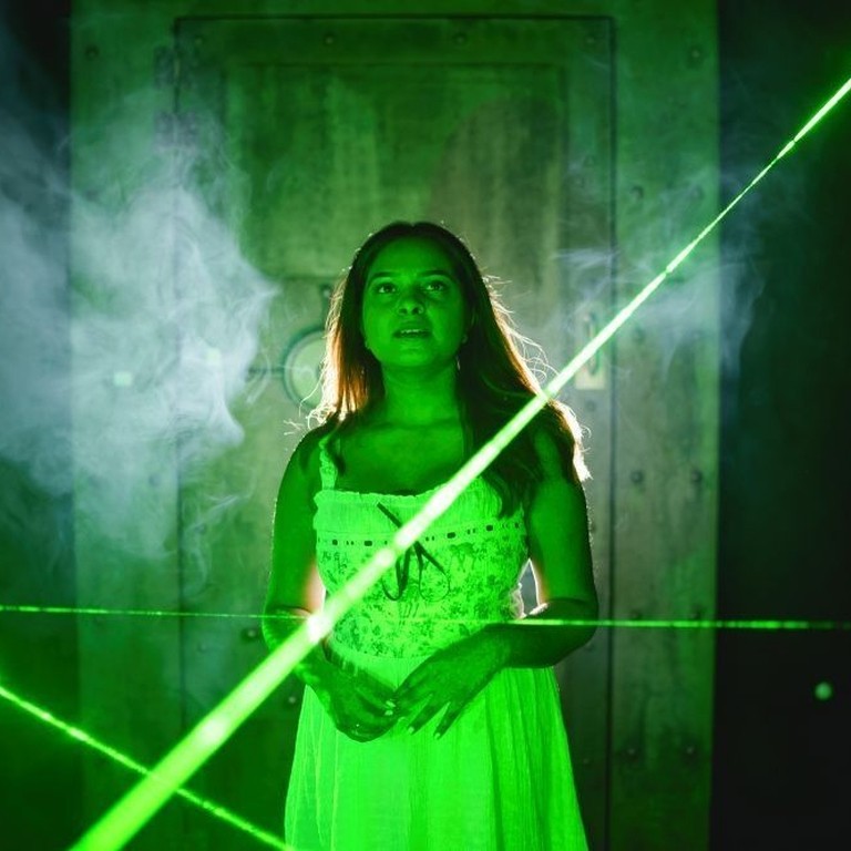 A woman enjoying the interactive escape room laser experience.