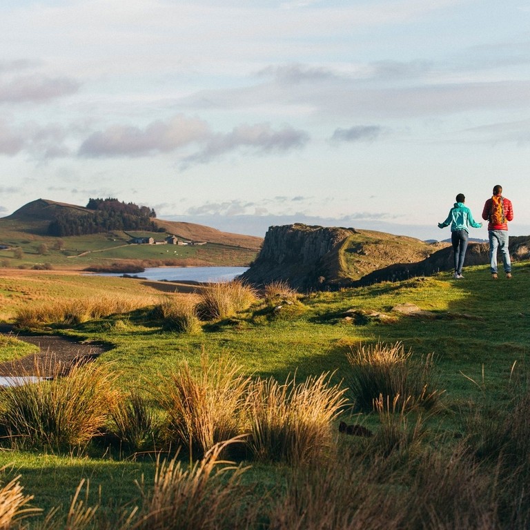 Dos personas caminando por una llanura con vistas a las montañas