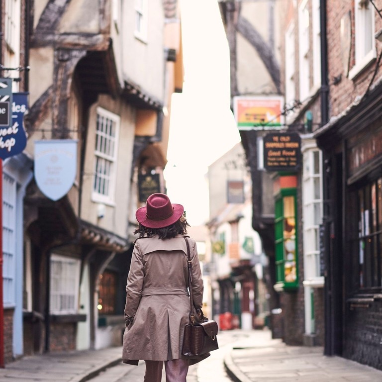 Woman wearing trench coat and pink hat walking