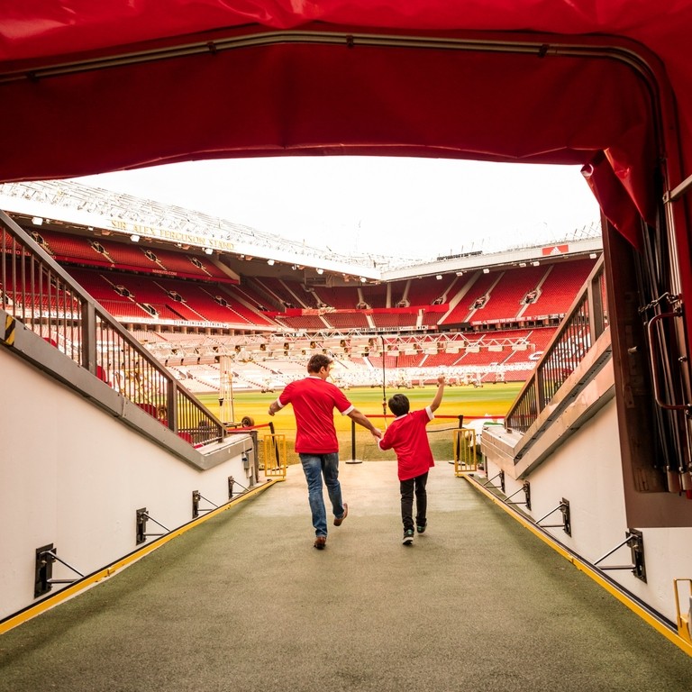 A man and boy in stadium tunnel looking out to pitch 