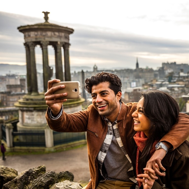 A young couple taking a selfie of view over historic town