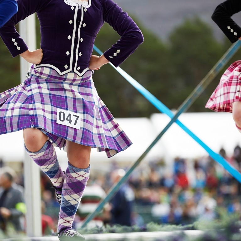 Three kilted girls Scottish dancing on stage