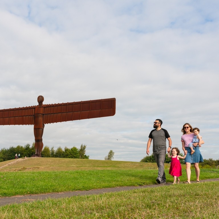 A family walking in front of the iconic Angel of the North, found just south of Newcastle Gateshead