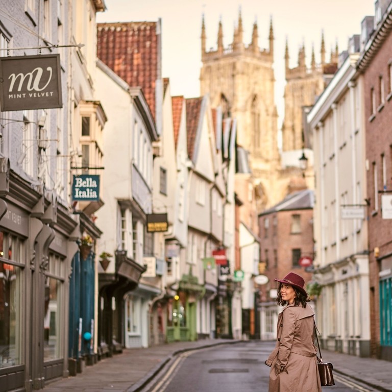 Woman wearing trench coat and pink hat walking