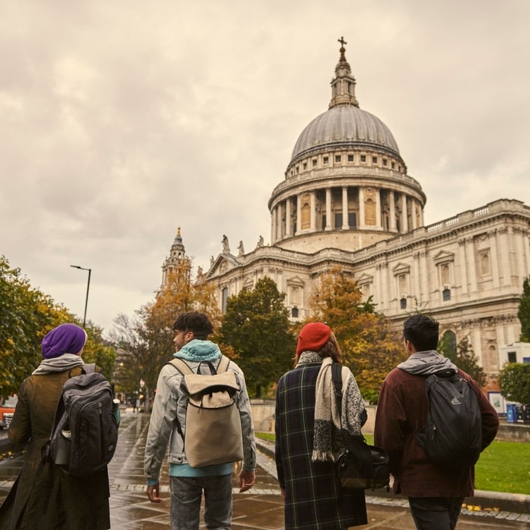 Four young people walking and talking on pavement