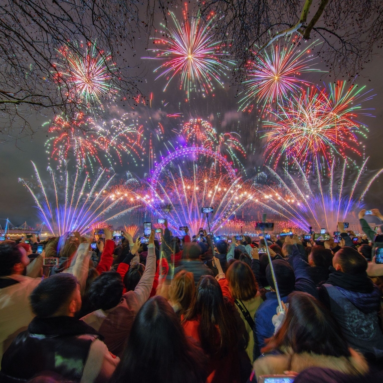 A crowd watching fireworks celebrating New Year's Eve