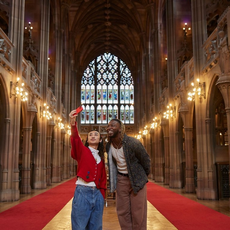 Two men taking a selfie inside a large library.