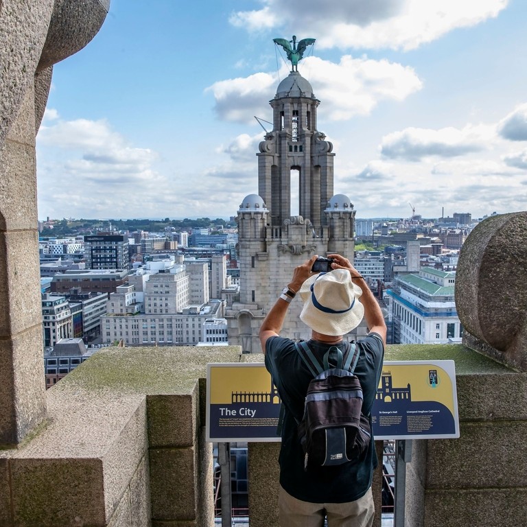 Gentleman photographing the tower in the skyline from the roof of the Royal Liver Building 360, Merseyside.