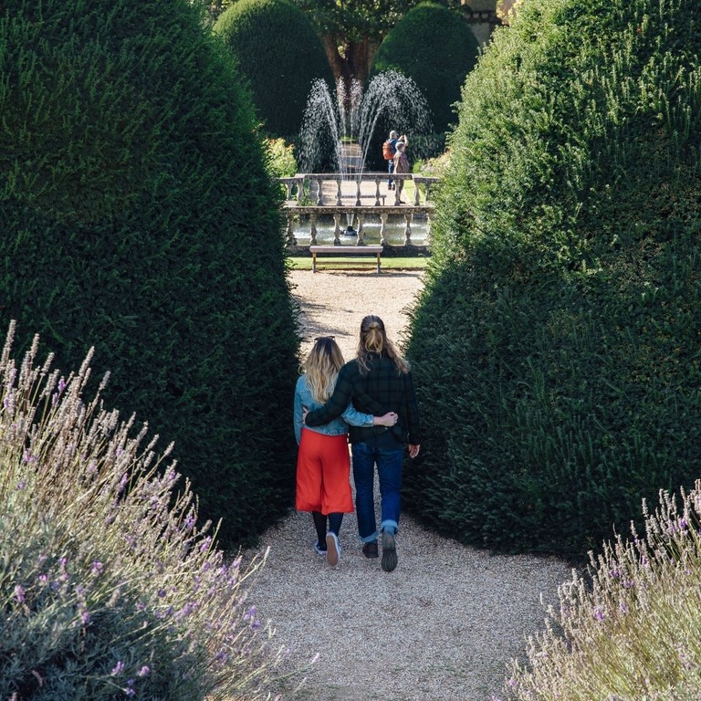 Pärchen, das sich im Garten in der Nähe eines Springbrunnens umarmt