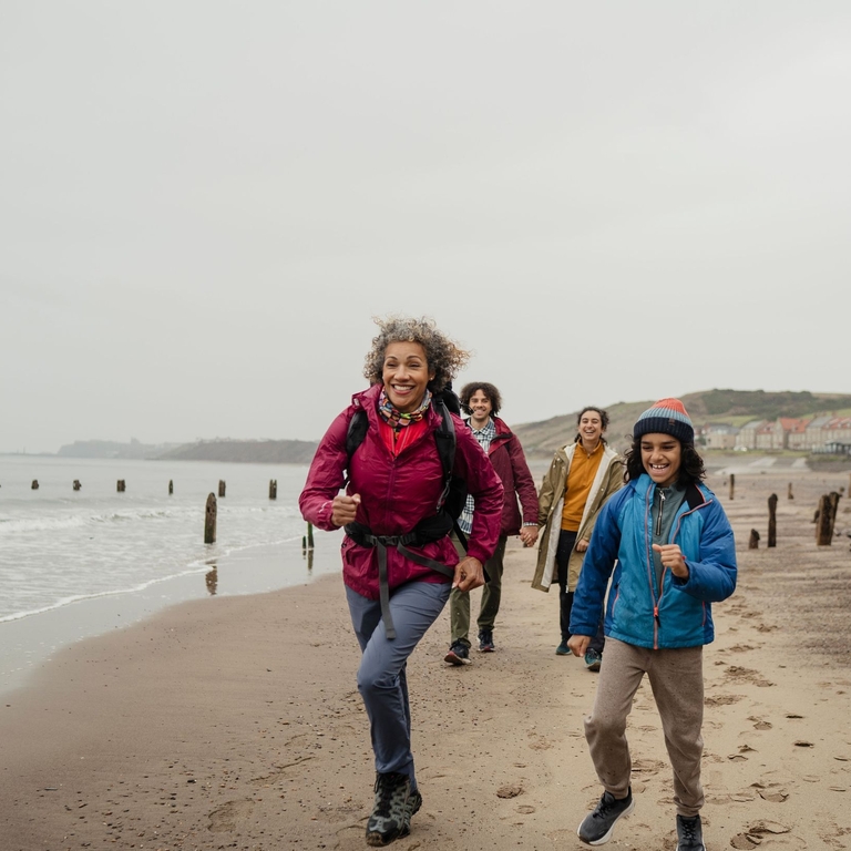 A family walking on the beach, two running ahead smiling