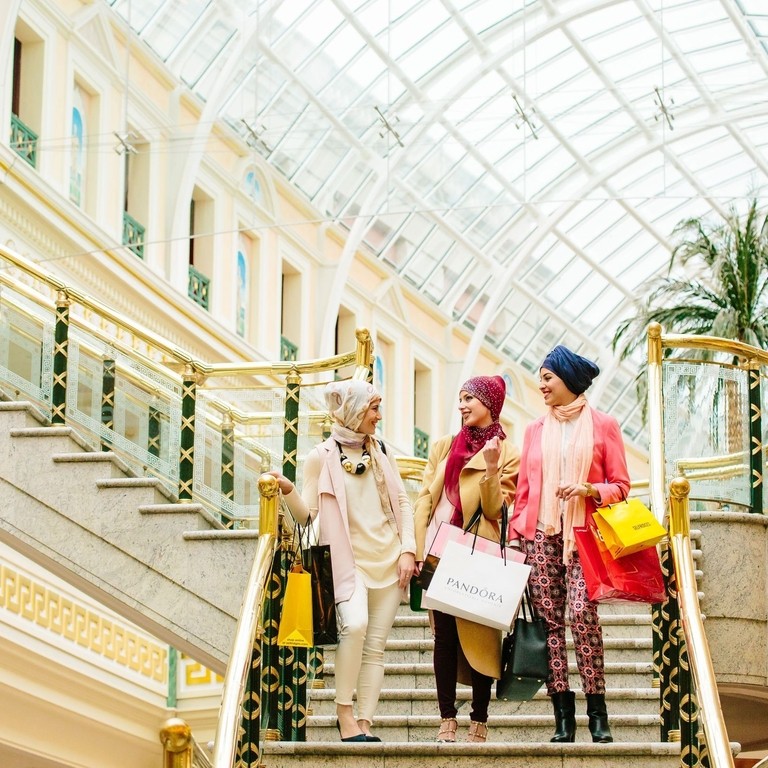 Tres mujeres, con bufanda, caminando con bolsas de la compra