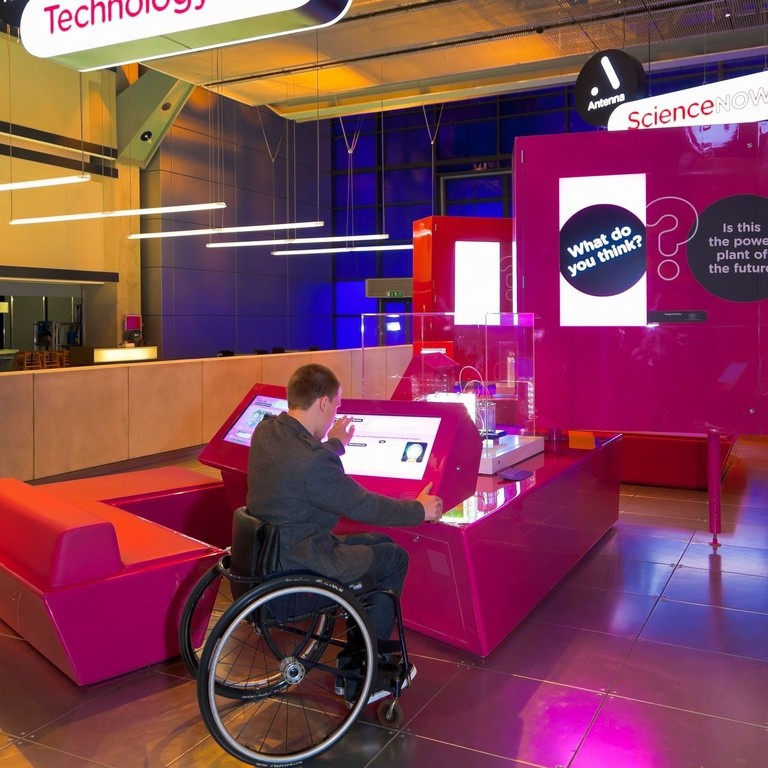 Male wheelchair user using interactive display at museum