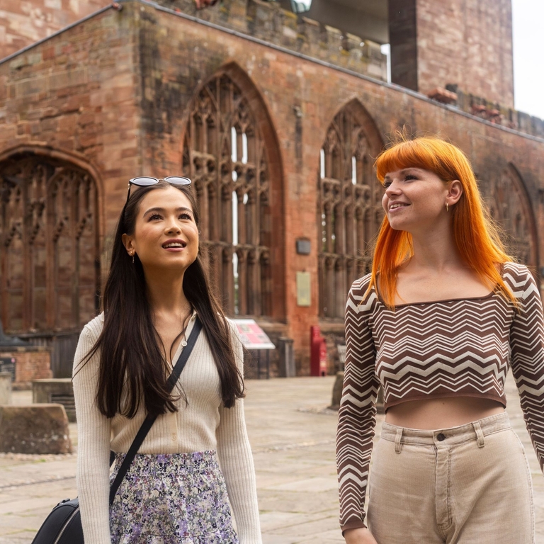 Two women explore the ruins within the grounds of a Cathedral