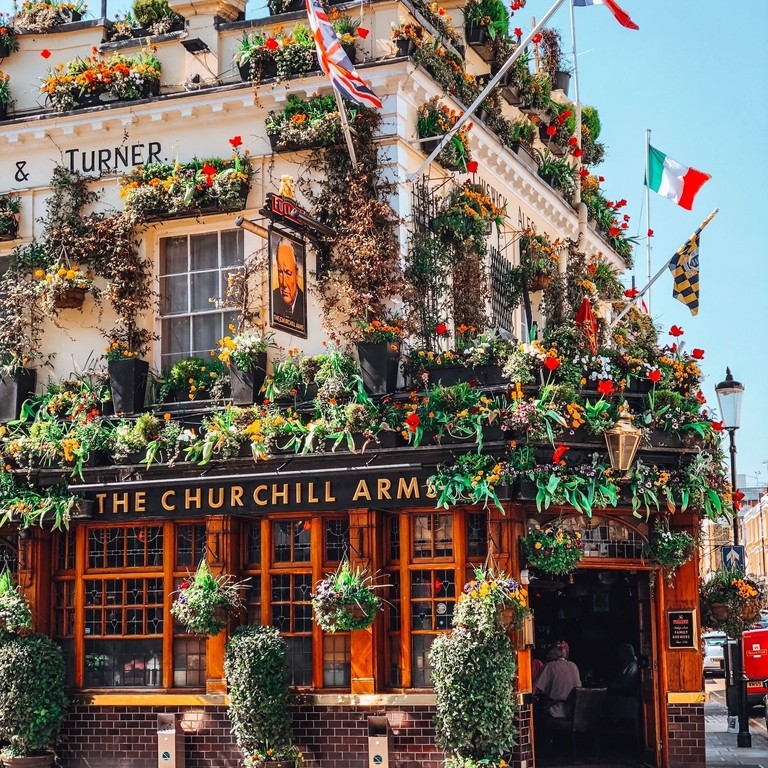 Pub decorato con numerosi vasi di fiori e bandiere