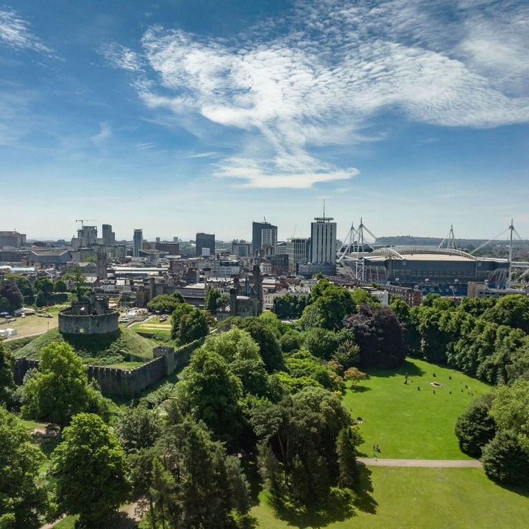 View of Bute Park, Cardiff from above, with green trees in the foreground and blue skies