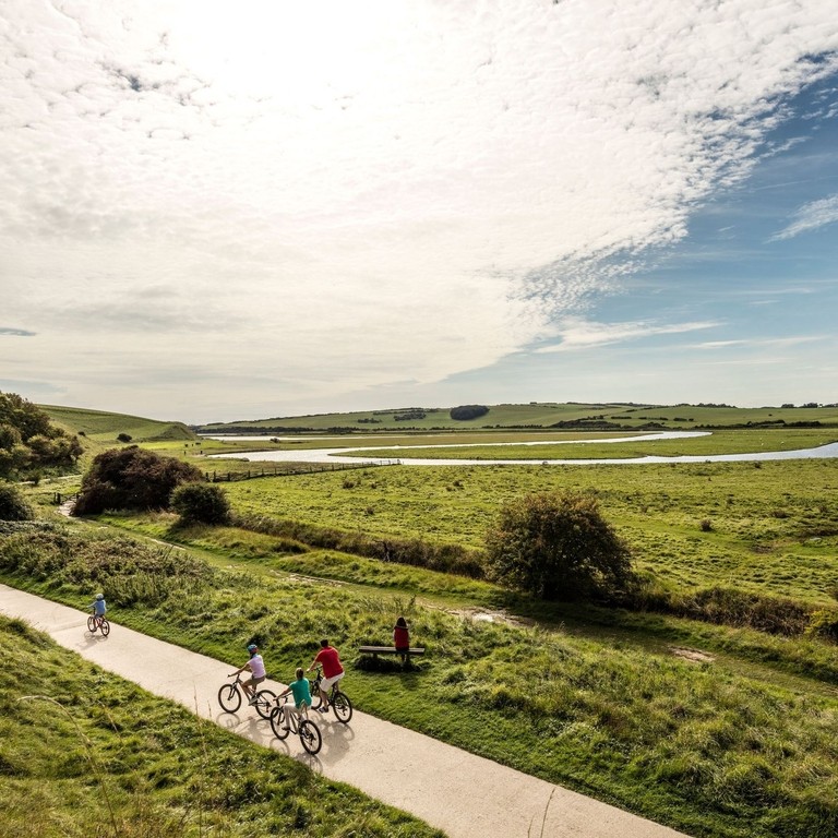 Una familia en bicicleta por un sendero que atraviesa un paisaje abierto