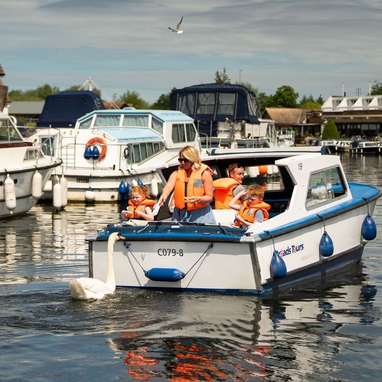 A family riding on a boat in the Norfolk Broads