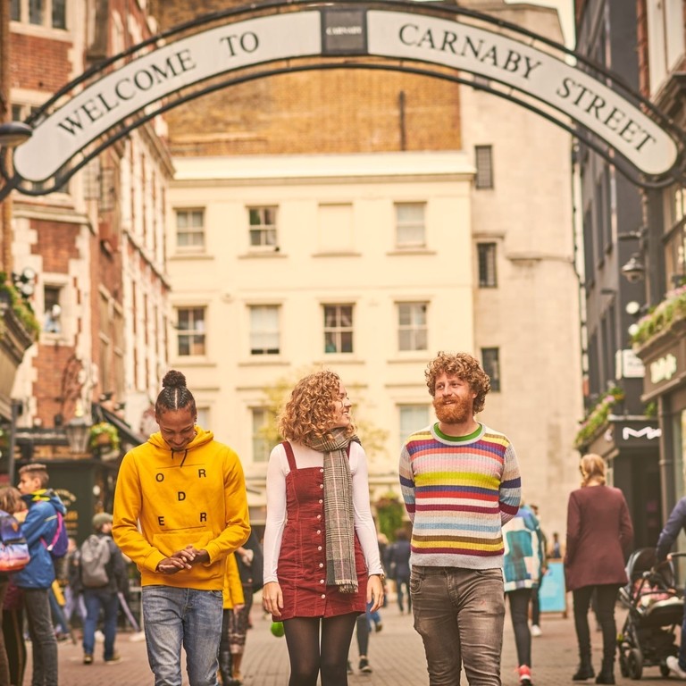 One young woman and two young men, walking down a street