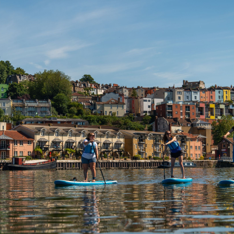 People paddleboarding on the river with the City of Bristol beyond