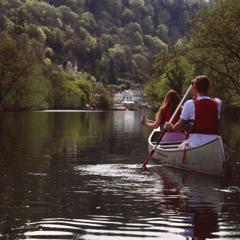 Two people canoeing along a river 