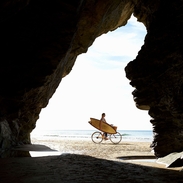 Una mujer pedalea por una playa de Cornualles con su tabla de surf