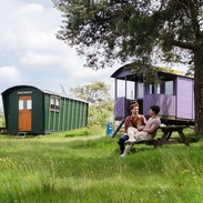Two men sat oustide a shepherds hut in the countryside