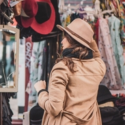 A woman trying on hats at a stall in Portobello Road Market, London