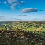 Frau in Wanderausrüstung, die auf einem Wanderweg am Hang spazieren geht und die Aussicht genießt