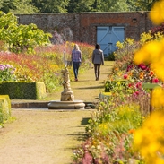 Two female friends walking through a formal garden