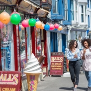 Two women walk down a street with ice creams