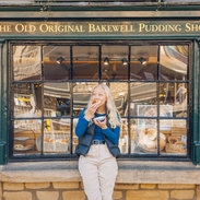 Woman eating bakewell tart in front of bakery