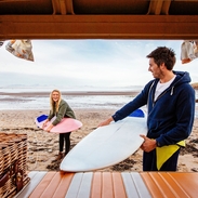 Young man and woman unloading surfboards from camper van
