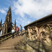 Three men walking down stone steps of a monument