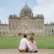 A man and a woman sit on a step looking towards a heritage building