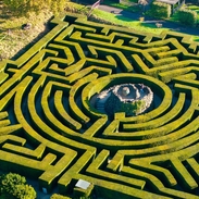 Aerial view of woman walking up the central tower of a hedge maze