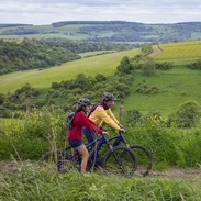 A man and a woman stand with bicycles wearing helmets