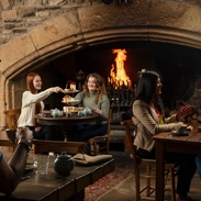 Two women enjoy an Afternoon Tea in front of a fire in an traditional historic pub