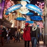 Ein Paar geht unter Weihnachtsbeleuchtung eine Straße entlang