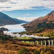View of valley in the Highlands and the Glenfinnan Viaduct, steam train on the tracks, Loch Shiel in the background
