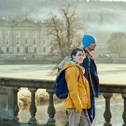 A young couple standing at the balustrade of a stone bridge