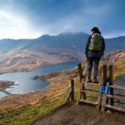 Walker on a wooden lookout overlooking a vast mountain range and lake panorama