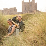 A couple walking in the sand dunes near Bamburgh Castle