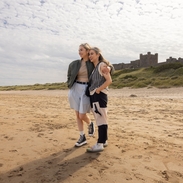 Two women hugging on the beach near a castle