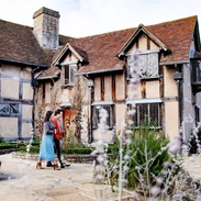Couple walking around the exterior of Shakespeare's Birthplace, Stratford-upon-Avon, Warwickshire, England