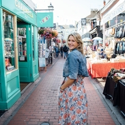 Smiling woman in denim jacket standing between shops